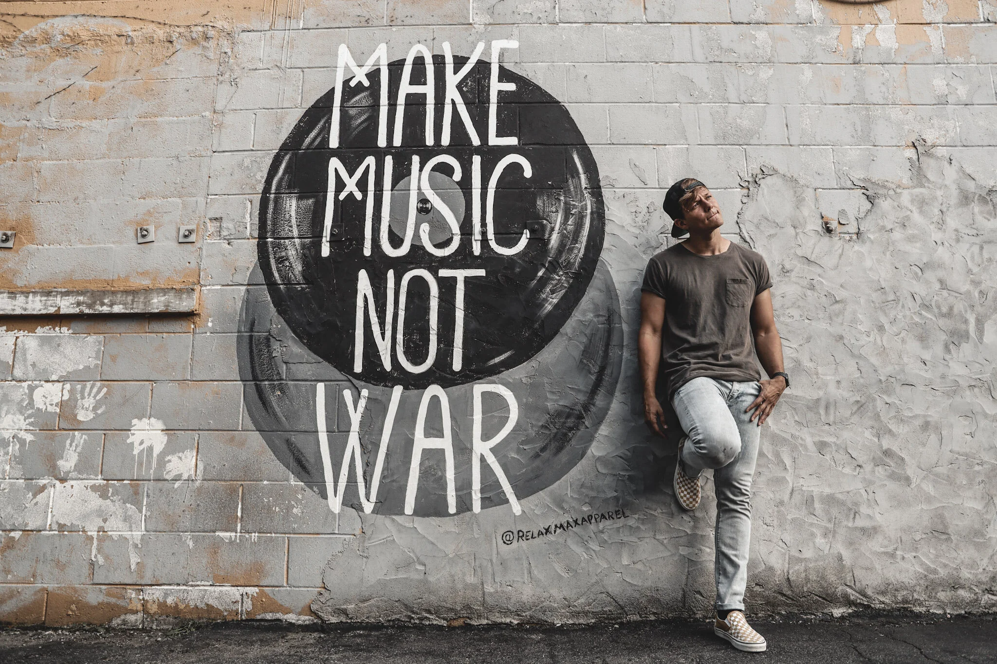 Tyler Ward standing beside a Make Music Not War mural